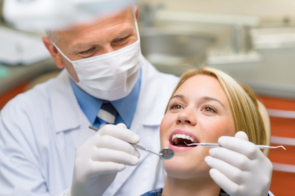 A dentist is examining a woman's teeth.