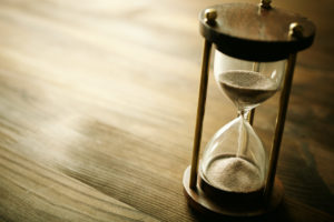 A sand hourglass sitting on a wooden table.