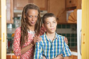An african-american woman and her son standing in a kitchen.